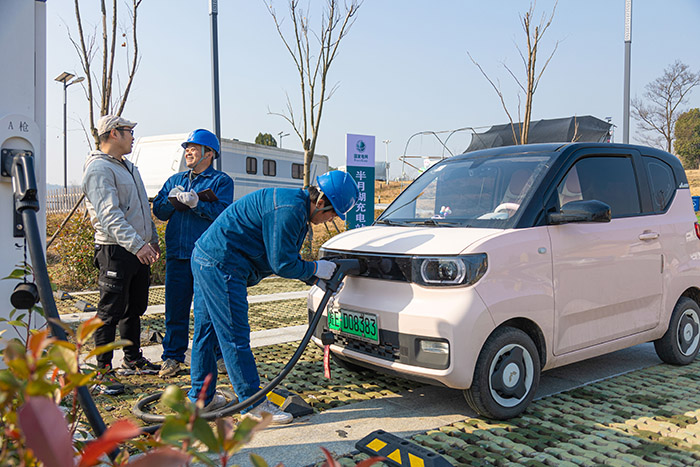 國網(wǎng)馬鞍山供電公司員工在和縣善厚鎮(zhèn)半月湖電動汽車充電站為車主解答充電疑問。高孫浩攝