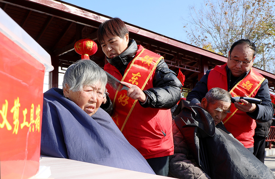 志愿者在潁東區(qū)老廟鎮(zhèn)大集上為村民理發(fā)。宿飛攝