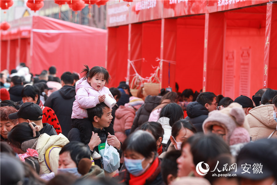 安徽南陵，一位小朋友騎在家長(zhǎng)肩上逛年貨集市。人民網(wǎng)記者 張俊攝